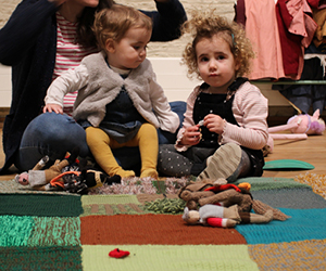 Two young children sitting on an interactive fabric field in a Mini Museum session.