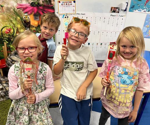 Three reception-aged children hold puppets they created during a workshop.