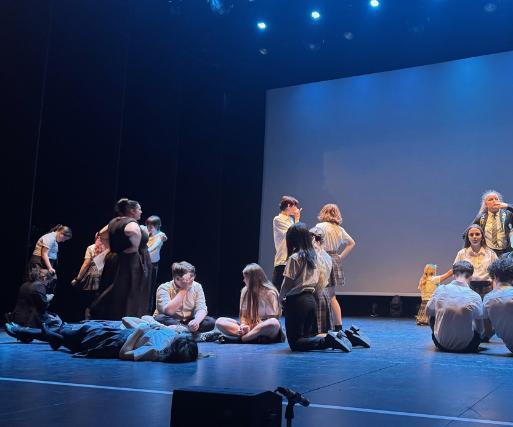 A class of secondary school children wearing uniform perform on the Newark Palace Theatre stage.