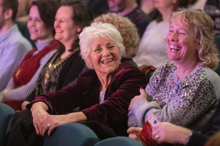 two ladies laughing in the auditorium audience