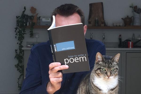 Promotional image for Brian Bilston featuring a person holding a poetry book beside a tabby cat in a home setting.
