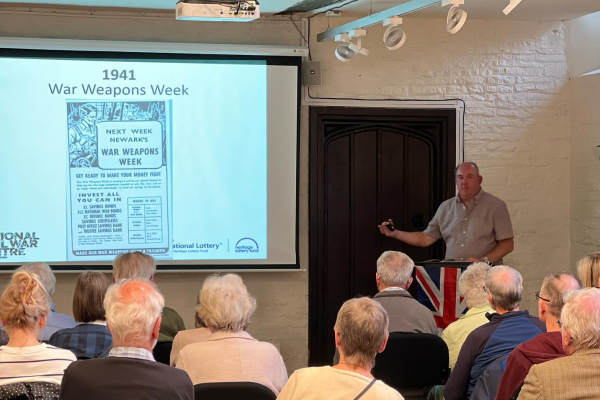 Speaker presenting a history talk to an audience at the National Civil War Centre, with a projection about Newark’s 1941 War Weapons Week campaign.